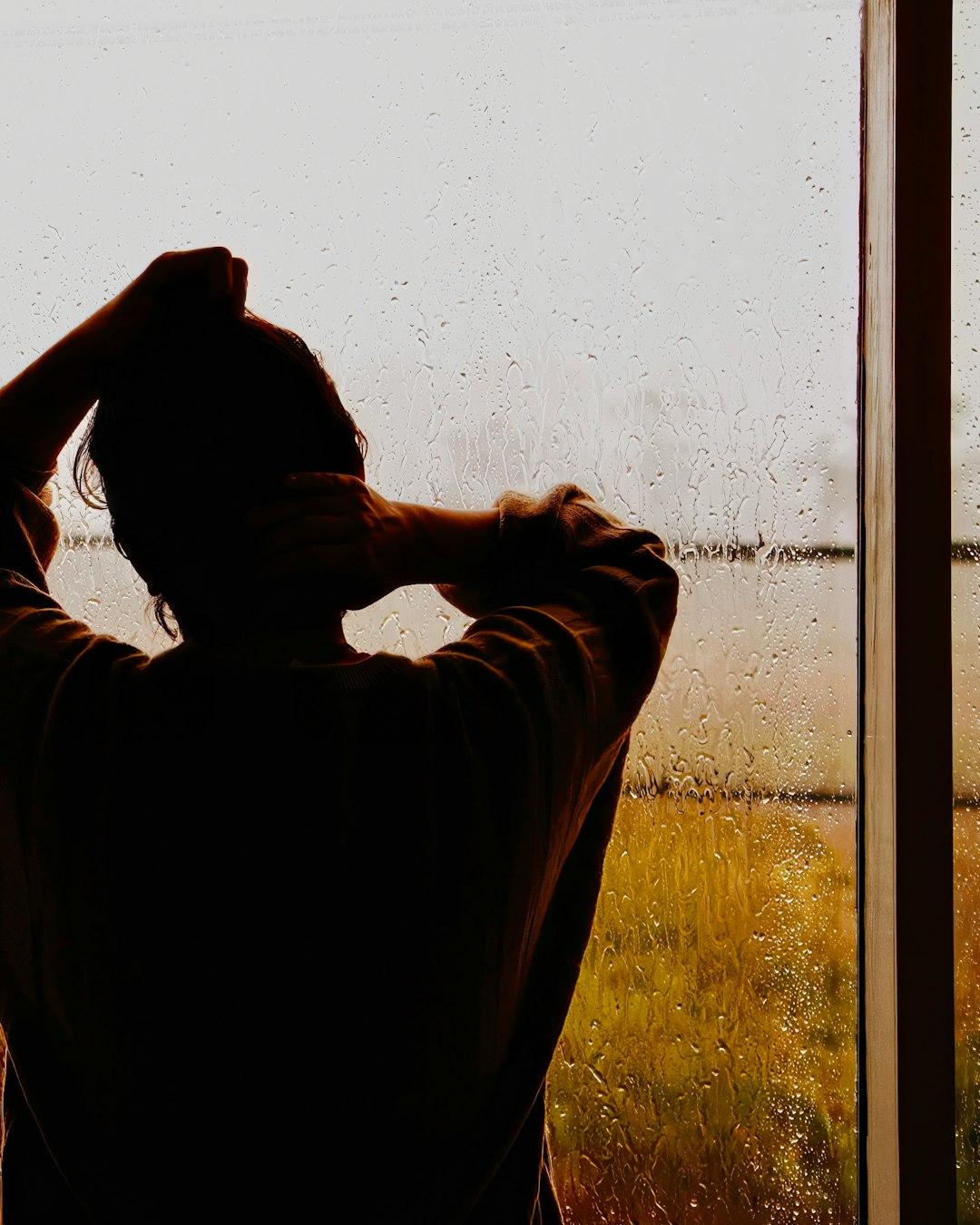 Nachdenkliche Person, die in sich gekehrt aus dem Fenster blickt