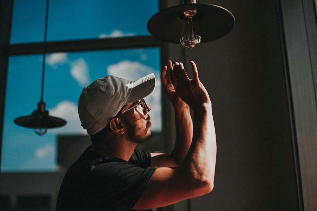 repair person replacing a home ceiling lightbulb