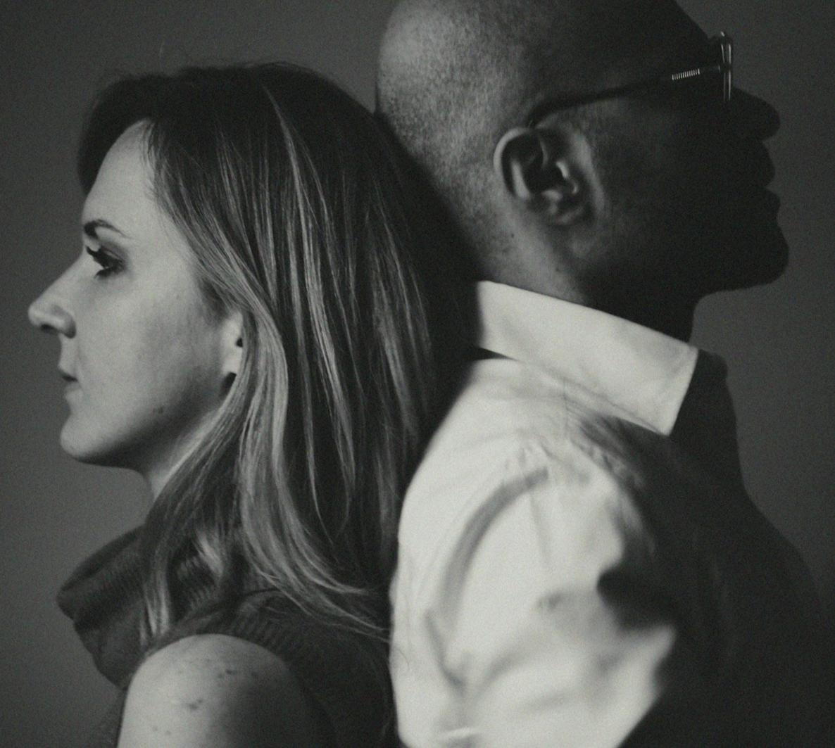 A middle-aged couple sitting apart on a sofa in a tense, quiet moment