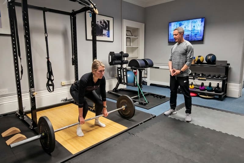 A coach guiding a client through strength training