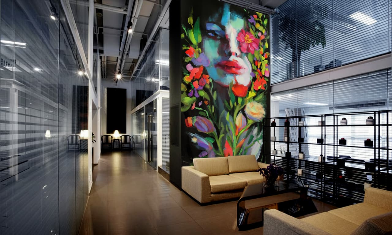 An artist painting a large mural across an interior wall
