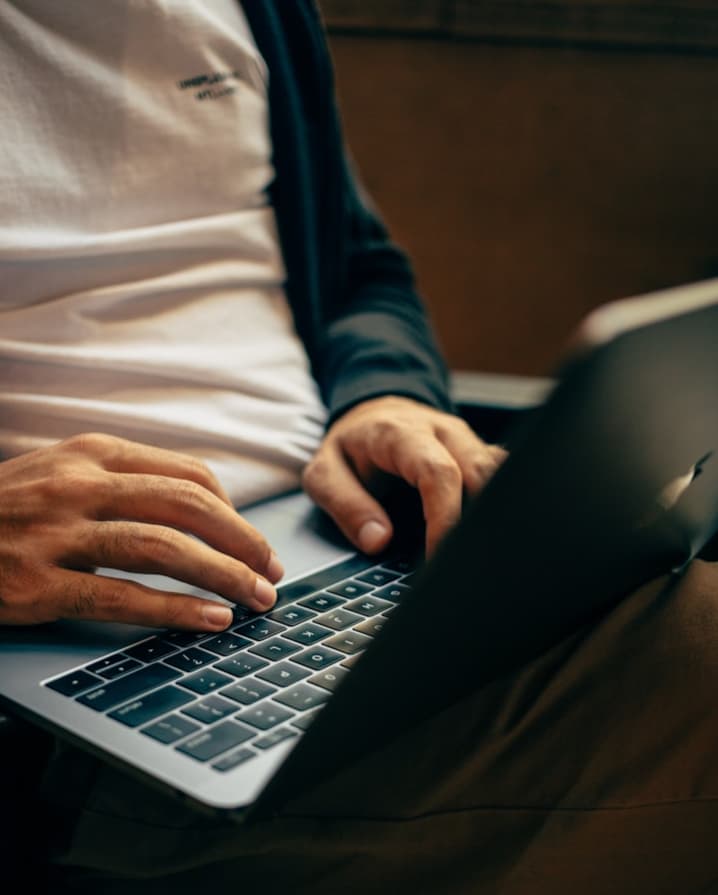 A man seated while browsing his laptop on his lap