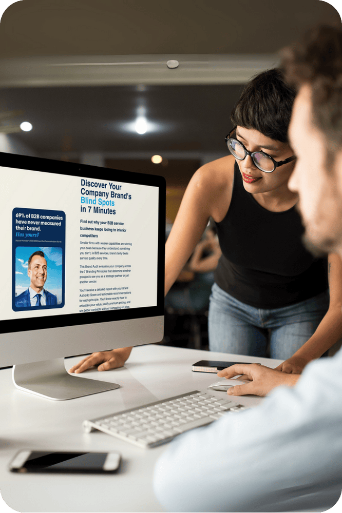 Business professionals reviewing IKONIC Brands Company Brand Scorecard on desktop computer - Brand Identity Model assessment showing 7-minute brand audit for B2B companies with marketing strategy insights