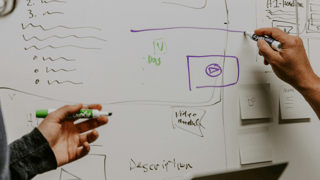 2 experts discussing strategy in front of a white board.