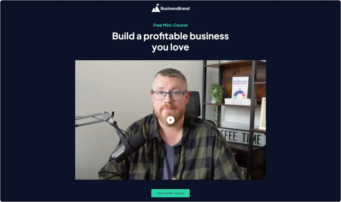 BusinessBrand free mini-course landing page: 'Build a profitable business you love' with a video thumbnail of a bearded man at a Shure…